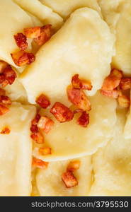 Closeup of dumplings sprinkled with pork scratchings as food background. Traditional polish (Poland) cuisine.