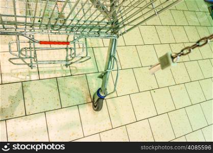 Closeup of empty metal shopping trolley cart on tiled floor in gorcery store supermarket.