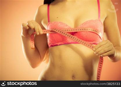 Closeup of female body. Fitness woman fit girl in pink lingerie with measure tape measuring her chest breasts