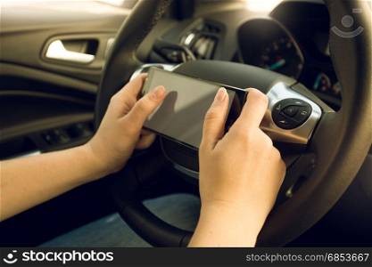 Closeup of female driver using smartphone while driving car