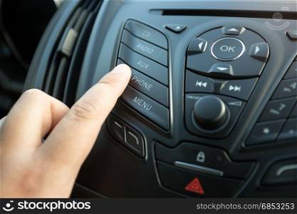 Closeup of female finger pressing radio button on car control panel