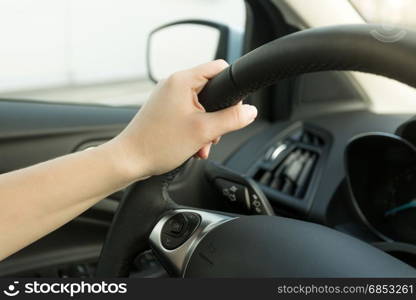 Closeup of female hand holding car steering wheel