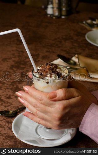 Closeup of female hands holding cup of latte
