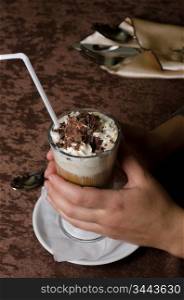 Closeup of female hands holding cup of latte with chocolate