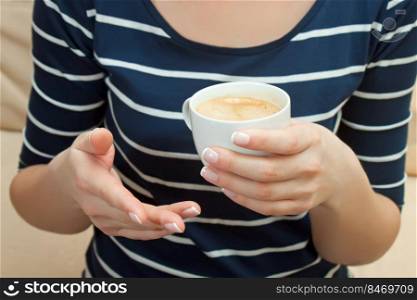 Closeup of female hands with a cup of coffee. Girl in dark blue striped top holding cup of coffee.. Closeup of female hands with a white cup of cofee