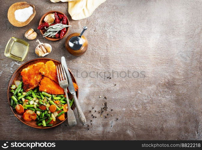 Closeup of fried fish with green beans on plate on dark background