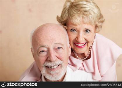 Closeup of good looking senior couple. Shallow depth of field with focus on husband in foreground.