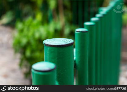 Closeup of green steel fence panel serves the important part of this area with exterior garden background, selective focus.