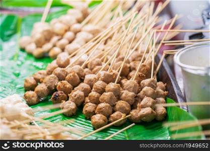 Closeup of Grilled meatballs on bamboo sticks background, thai street food market
