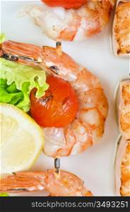 Closeup of grilled shrimps and tomatoes on bamboo sticks with salmon