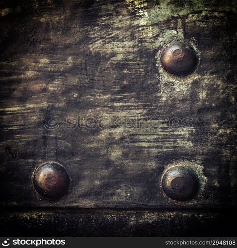 Closeup of grunge black metal plate with rivets and screws as background or texture. Square format.