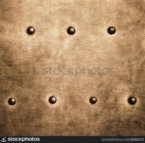Closeup of grunge gold brown metal plate with rivets and screws as background or texture