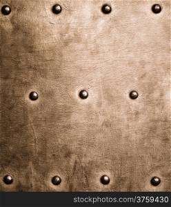 Closeup of grunge gold brown metal plate with rivets and screws as background or texture