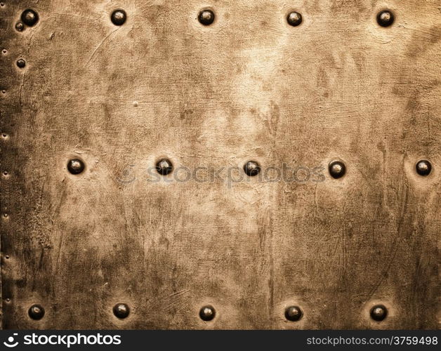 Closeup of grunge gold brown metal plate with rivets and screws as background or texture