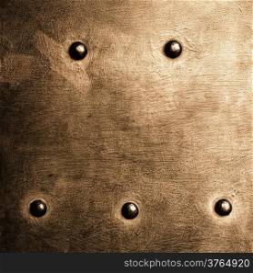 Closeup of grunge gold brown metal plate with rivets and screws as background or texture. Square format.