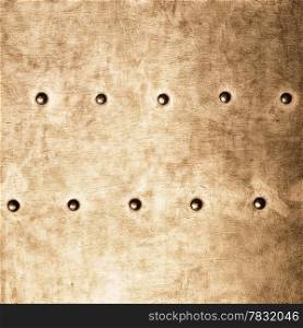 Closeup of grunge gold brown metal plate with rivets and screws as background or texture. Square format.
