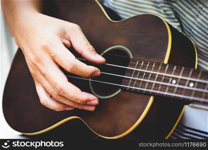 Closeup of guitarist hand playing guitar. Musical instrument concept. Outdoors and Leisure theme. Selective focus on left hand. Vintage country folk guitar with music singer. Close up entertainer hand