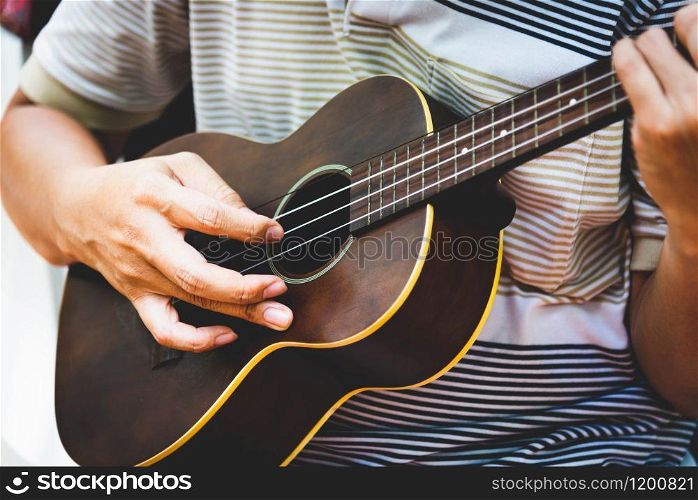 Closeup of guitarist hand playing guitar. Musical instrument concept. Outdoors and Leisure theme. Selective focus on left hand. Vintage country folk guitar with music singer. Close up entertainer hand