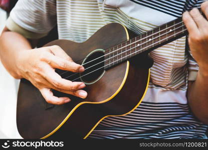 Closeup of guitarist hand playing guitar. Musical instrument concept. Outdoors and Leisure theme. Selective focus on left hand. Vintage country folk guitar with music singer. Close up entertainer hand