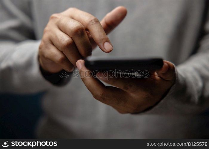 Closeup of Hand Using Mobile Phone. Cropped image. Selective Focus. Using Smartphone for Communication, Texting, Reading or Playing Game