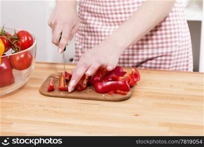 closeup of hands cutting vegetables. closeup of hands cutting red paprika on a chopping board