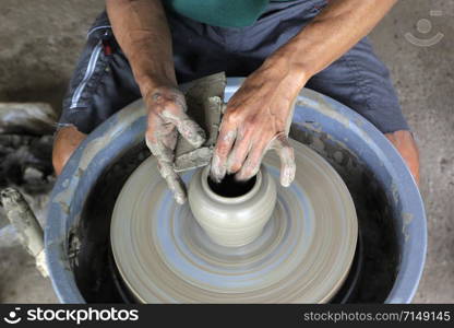 closeup of hands making pottery on pottery wheel