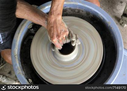 closeup of hands making pottery on pottery wheel