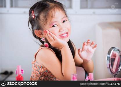 Closeup of happy kid is beautiful make up face with cosmetics toy, Asian adorable funny little girl making makeup her face, Learning activity to be woman, fashion beauty children at home