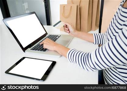 Closeup of happy young woman holding credit card inputting card information while and using laptop computer at home. Online shopping concept