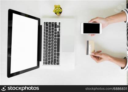 Closeup of happy young woman holding credit card inputting card information while and using smart phone at home. Online shopping concept