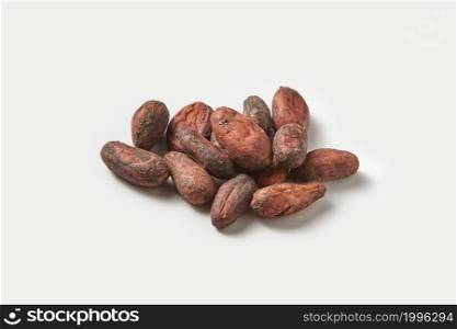 Closeup of heap of fresh organic beans of exotic Theobroma cacao tree placed on white background. Pile of raw unpeeled cocoa beans