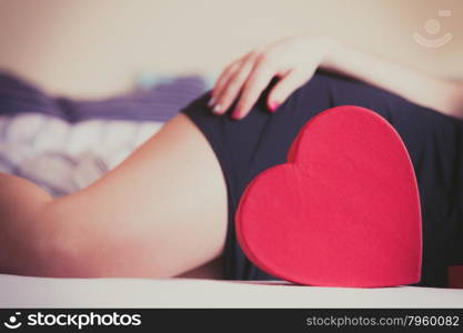 Closeup of heart shape box and woman legs.. Closeup of red heart shape box and woman legs. Valentines day love.