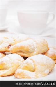 Closeup of homemade jam filled crescent rolls and white cups of tea