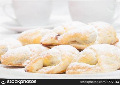 Closeup of homemade jam filled crescent rolls and white cups of tea