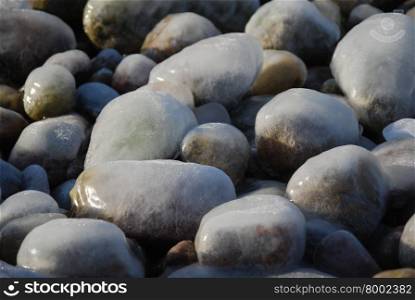 Closeup of ice covered pebbles by a coast