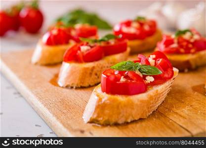 Closeup of Italian bruschetta with tomato, basil and garlic on a chopping board