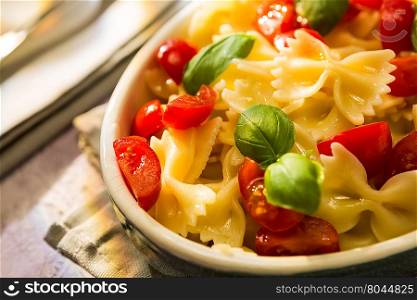 Closeup of Italian Farfalle pasta with tomatoes and basil over a colored background. Closeup of Italian Farfalle pasta with tomatoes and basil