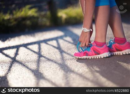 Closeup of jogging woman tying running shoe