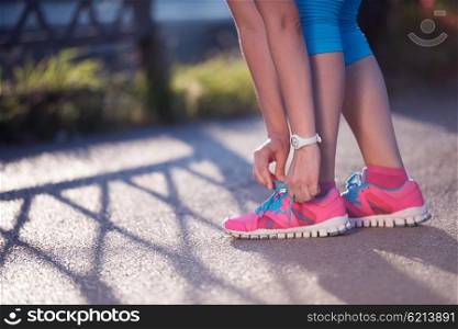 Closeup of jogging woman tying running shoe