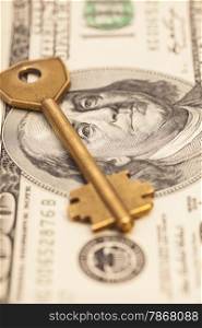 Closeup of key on hundred dollar bills