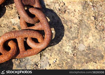 Closeup of large rusty old used chain links on stone background