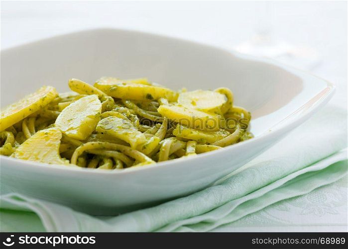 Closeup of linguine pasta with pesto genovese and potatoes over a table. Closeup of linguine pasta with pesto genovese and potatoes