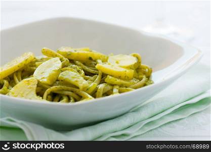 Closeup of linguine pasta with pesto genovese and potatoes over a table. Closeup of linguine pasta with pesto genovese and potatoes