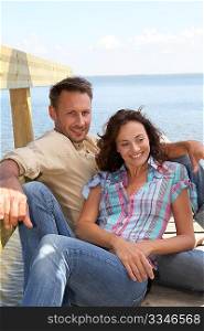 Closeup of loving couple sitting on a pontoon by a lake