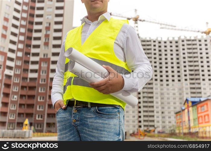 Closeup of male engineer holding blueprints and documents