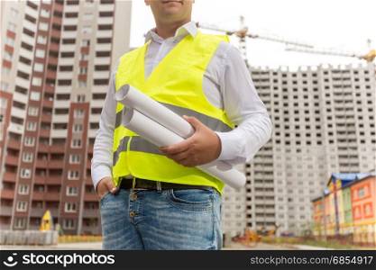 Closeup of male engineer holding blueprints and documents