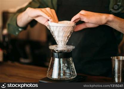 Closeup of male hands prepares coffee pot standing on bar counter.