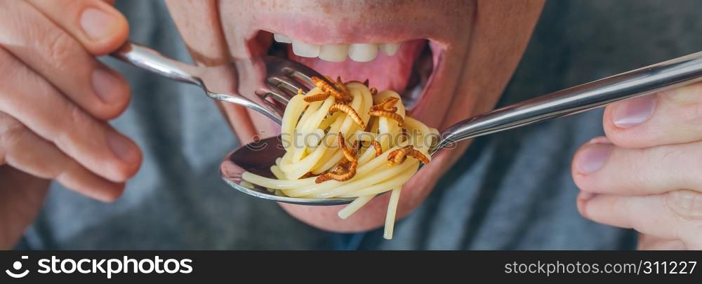 Closeup of man eating spaghetti with crispy worms. Man eating spaghetti with worms