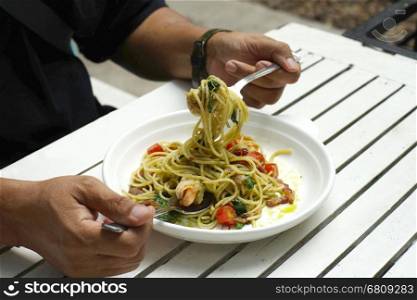 closeup of man hands holding fork and spoon during eating spaghetti