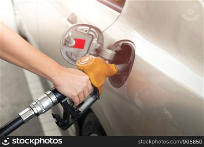 Closeup of man pumping gasoline fuel in car at gas station. Fuel nozzle with hose in hand.